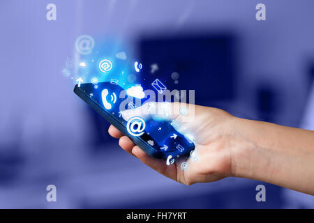 Business man holding smart phone with media icons Stock Photo
