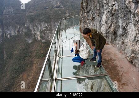 Tongren, China's Guizhou Province. 24th Feb, 2016. Tourists walk on a glass skywalk in the National Mine Park of Tongren City, southwest China's Guizhou Province, Feb. 24, 2016. The 1,005-meter-long and 1.6-meter wide glass skywalk, with more than 100 meters above the valley bottom, has passed a safety test and will be opened to the public in May. Credit:  Liu Xu/Xinhua/Alamy Live News Stock Photo