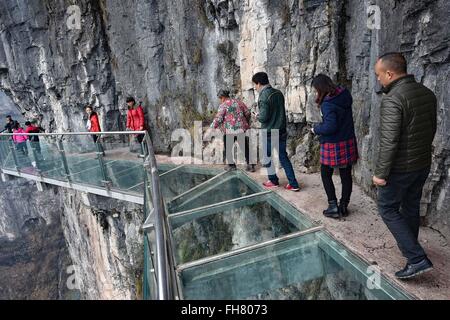 Tongren, China's Guizhou Province. 24th Feb, 2016. Tourists walk on a glass skywalk in the National Mine Park of Tongren City, southwest China's Guizhou Province, Feb. 24, 2016. The 1,005-meter-long and 1.6-meter wide glass skywalk, with more than 100 meters above the valley bottom, has passed a safety test and will be opened to the public in May. Credit:  Liu Xu/Xinhua/Alamy Live News Stock Photo