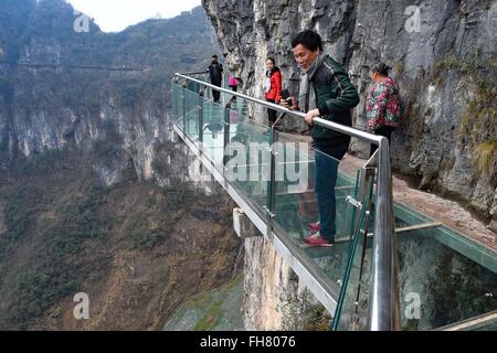 Tongren, China's Guizhou Province. 24th Feb, 2016. Tourists walk on a glass skywalk in the National Mine Park of Tongren City, southwest China's Guizhou Province, Feb. 24, 2016. The 1,005-meter-long and 1.6-meter wide glass skywalk, with more than 100 meters above the valley bottom, has passed a safety test and will be opened to the public in May. Credit:  Liu Xu/Xinhua/Alamy Live News Stock Photo