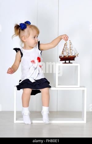 Little girl playing with toy boat in the studio Stock Photo