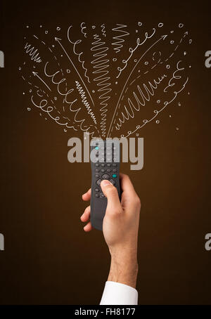 Hand with remote control and curly lines Stock Photo