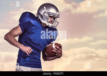 Composite image of american football player holding ball in mid-air Stock Photo