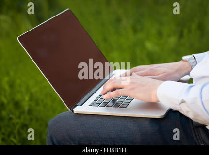 Businessman pressing modern laptop computer on colorful background Stock Photo