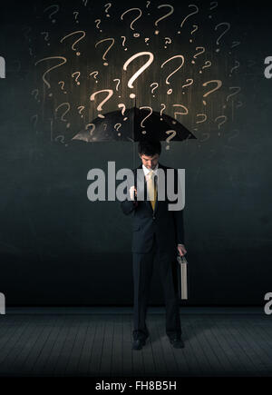 Businessman with umbrella and a lot of drawn question marks Stock Photo
