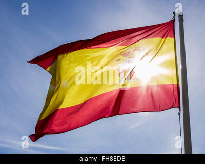 Spanish flag rippling in the breeze against a blue sky, Spain Stock Photo