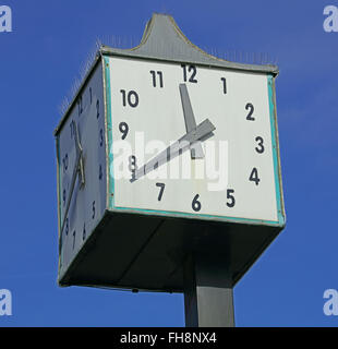 Large square white clock face mounted high up on a pole in the middle of a shopping precinct at 11-38 Stock Photo