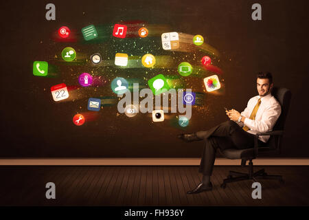 Business man sitting in office chair with tablet and colorful app icons Stock Photo