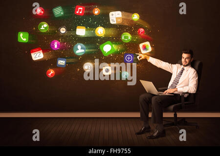 Business man sitting in office chair with laptop and colorful app icons Stock Photo