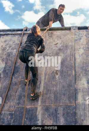 Participants in extreme obstacle race climbing wall Stock Photo