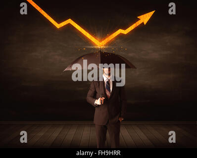 Businessman standing with umbrella keeping orange arrow Stock Photo