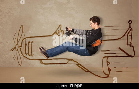 Funny pilot driving a hand drawn airplane on the wall Stock Photo