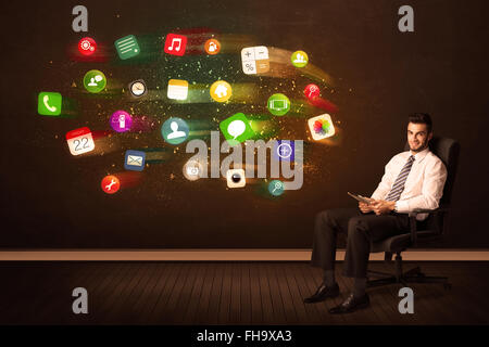 Business man sitting in office chair with tablet and colorful app icons Stock Photo
