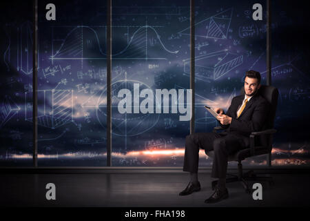 Businessman holding tablet in office room with graph charts on window Stock Photo