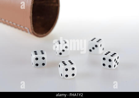 Five dices and a dice cup on a white table Stock Photo