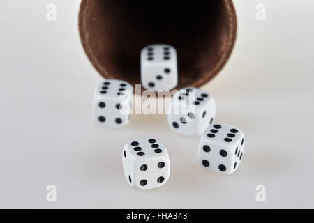 Five dices and a dice cup on a white table Stock Photo