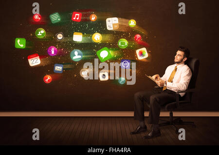 Business man sitting in office chair with tablet and colorful app icons Stock Photo
