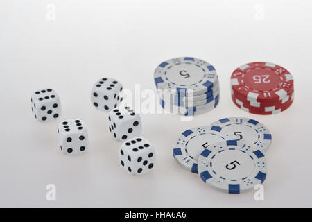 Five white dices and blue and white and red chips on a white table Stock Photo