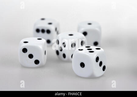 Five white dices with black eyes on a white glass table Stock Photo