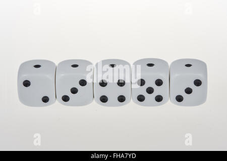 Five dices in a row, each showing one eye on the same side on a glass table Stock Photo