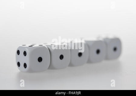 Five dices in a row, each showing one eye on the same side on a glass table Stock Photo