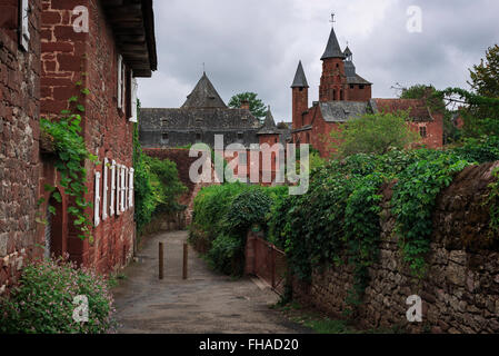 View on a path towards the tower of the church in red stone in the red village Collonges-la-Rouge in Dordogne area, France. Stock Photo