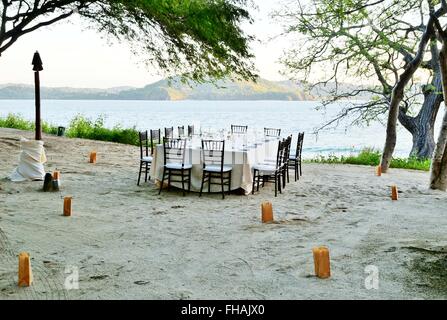 A romantic table set for dinner on the beach Stock Photo