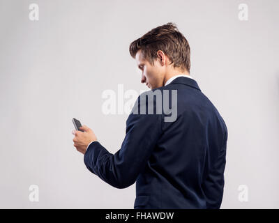 Hipster businessman with smartphone texting. Studio shot, back v Stock Photo