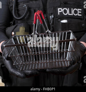 Police officer holding small wire shopping basket in shoplifting concept Stock Photo