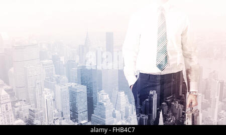 Business man standing on roof with city in the background Stock Photo