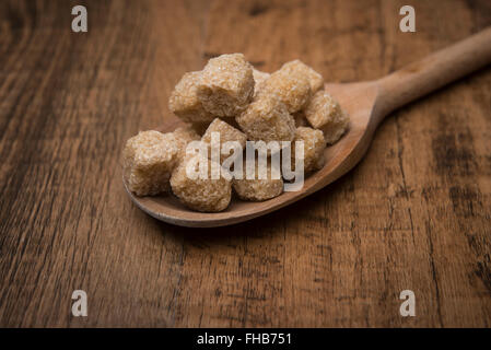 Pile of brown sugar cubes on a wooden spoon Stock Photo