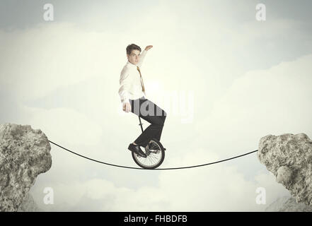 Brave business man riding an mono cycle between cliffs Stock Photo