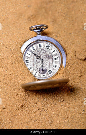 Old pocketwatch laying on the sand Stock Photo