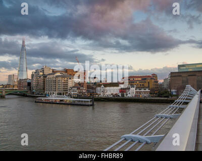 The Millennium Bridge and the Shard from the River Thames embankment in London Stock Photo