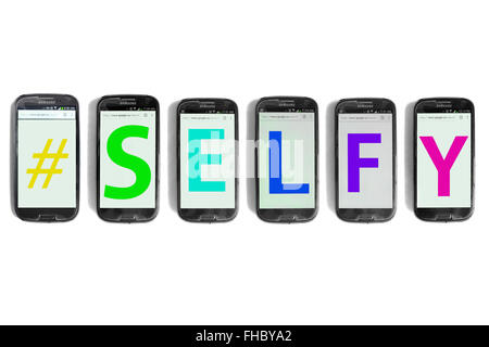 #Selfy written on the screens of smartphones photographed against a white background. Stock Photo