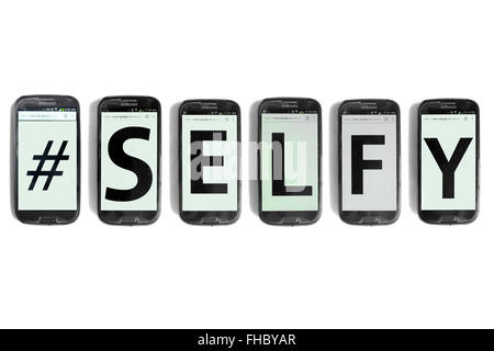 #Selfy written on the screens of smartphones photographed against a white background. Stock Photo