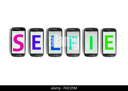 Selfie written on the screens of smartphones photographed against a white background. Stock Photo