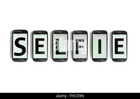 Selfie written on the screens of smartphones photographed against a white background. Stock Photo