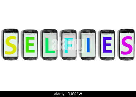 Selfies written on the screens of smartphones photographed against a white background. Stock Photo