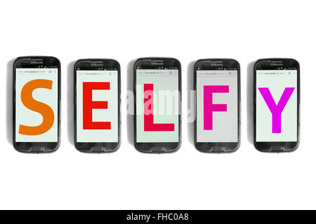 Selfy written on the screens of smartphones photographed against a white background. Stock Photo