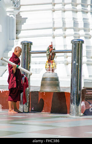 YANGON, MYANMAR - NOVEMBER 25, 2015 - Buddhist monk ringing the bell in the Shwedagon Pagoda on November 25, 2015 in Yangon. Stock Photo