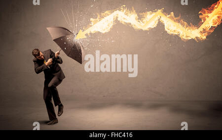 Business man defending himself from a fire arrow with an umbrella Stock Photo