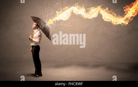Business man defending himself from a fire arrow with an umbrella Stock Photo