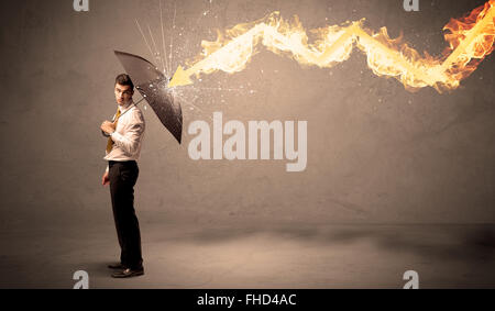 Business man defending himself from a fire arrow with an umbrella Stock Photo
