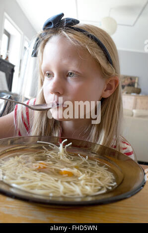 Polish girl age 8 quietly eats her noodle soup at home. Zawady Central Poland Stock Photo