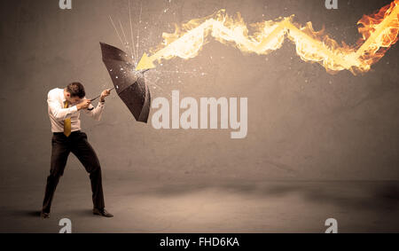 Business man defending himself from a fire arrow with an umbrella Stock Photo