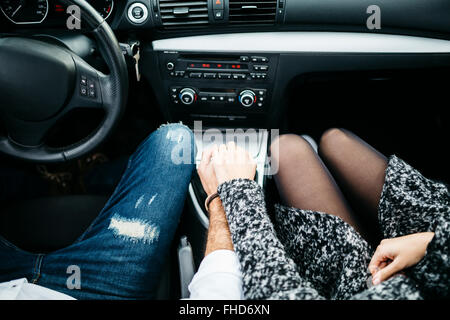 Young couple driving in a car holding hands Stock Photo