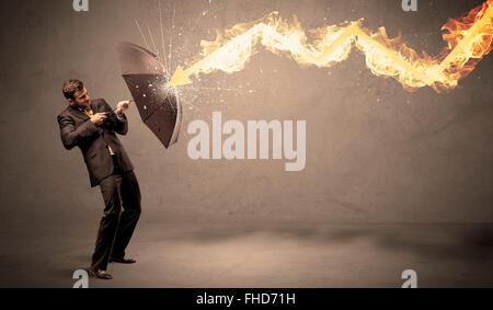 Business man defending himself from a fire arrow with an umbrella Stock Photo