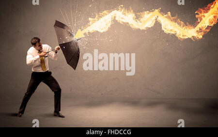 Business man defending himself from a fire arrow with an umbrella Stock Photo