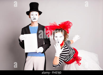 Portrait of happy smiling young actors showing blank signboard, with copyspace area for text or slogan, against grey background Stock Photo